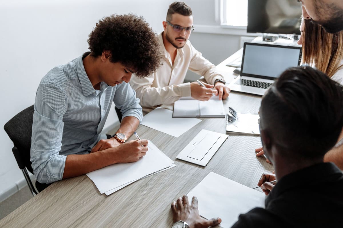 Equipo pequeño trabajando con portátiles y documentos